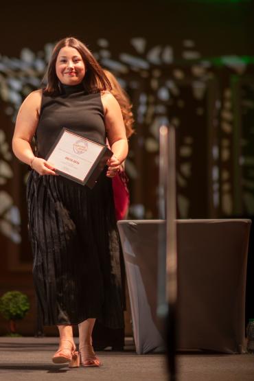 An OHIO student holds an award and walks across the stage at the Leadership Awards in the Baker University Center Ballroom.