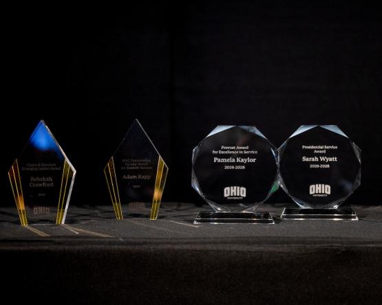 Several faculty awards are displayed on a table, including awards for Pamela Kaylor, Sarah Wyatt, Rebekah Crawford and Adam Rapp