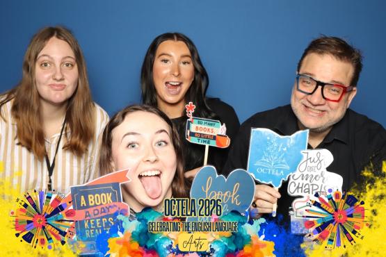 Three OHIO students and Dr. Kevin Cordi hold up signs related to the OCTELA Conference