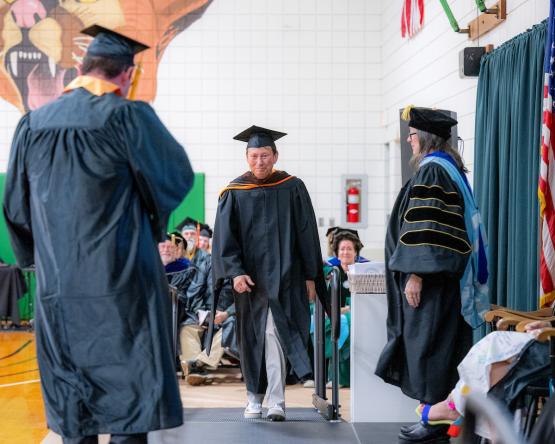 A. Victor Jones, who is wearing the graduation cap and gown, walks to the stage during the ceremony