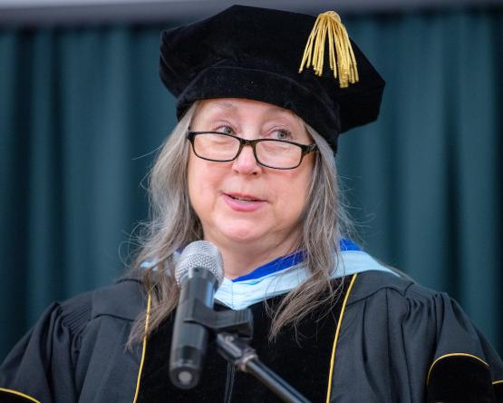 Interim Dean Marth Kline is shown wearing a commencement rob and hat at the ceremony