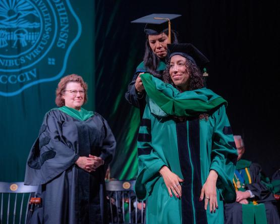 Student is hooded at HCOM commencement