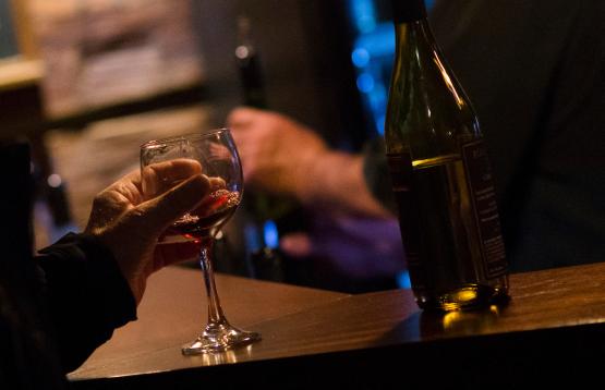 Wine glass and bottle sit on table