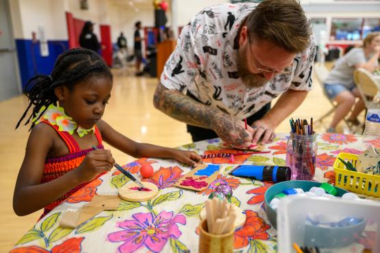 A man and a child work on crafts at a craft table at the Juneteenth Festival