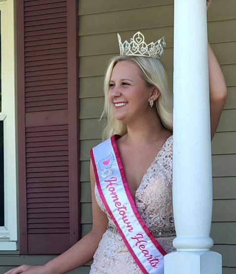 Sydney Bush is shown wearing her pageant crown and ribbon from the Hometown Hearts competition