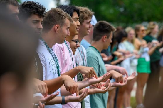 A group of students stand side-by-side, touching hands in a game