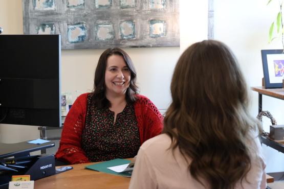 Jennifer Kellner-Muscar sits at a desk and assists an OHIO student