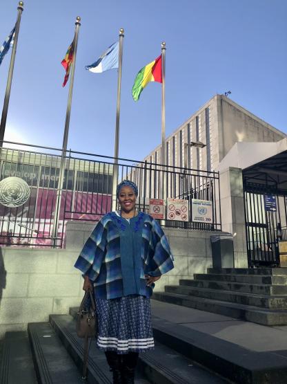 Dr. Lorraine Koobokile is shown standing outside a building underneath international flags