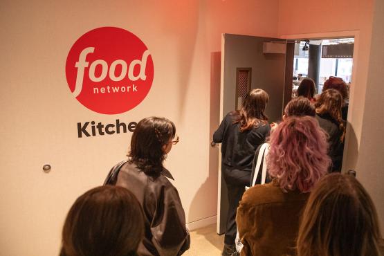 OHIO students walk through a doorway where the wall says Food Network Kitchen