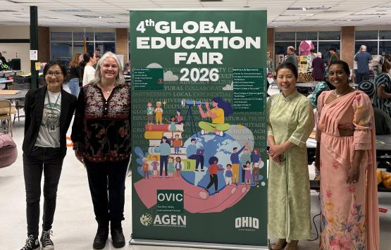 Four OHIO representatives stand in front of the Global Education Fair banner at one of the events