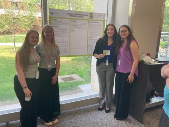 Four OHIO students stand by their research presentation poster
