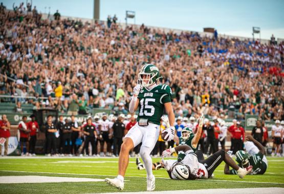 An OHIO Football player celebrates in the end zone in front of a large crowd  in Peden Stadium