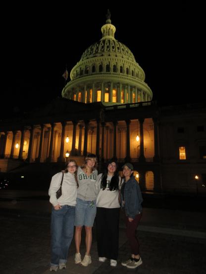 Katie Raines stands with other OHIO interns outside of a government building at night while in Washington, D.C.