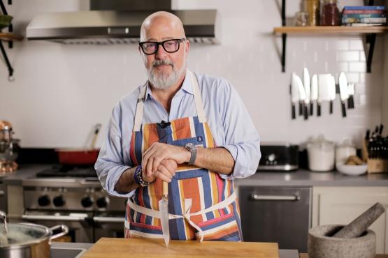Andrew Zimmern is shown at a counter in a kitchen