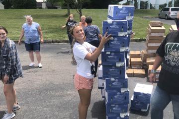 A student distributes boxes of food.
