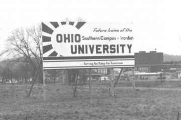 A black and white photo of an old billboard sign that reads "Future home of the Ohio University Southern Campus at Ironton ... Serving You Today For Tomorrow"