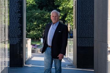 Ohio University graduate P. Joseph “Joe” Mullins, MFA ’78, stands among the names of the more than 10,000 West Virginians who served and died in the first four wars of the 20th century and whose sacrifice is memorialized in the West Virginia Veterans Memorial he designed.