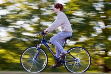 A student rides their bike on a sunny day