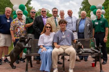 Family members and friends pose for a photo around one of the Bobcat Benches