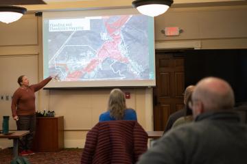 Natalie Kruse Daniels points at a map that says Flooding and Floodplain Mapping during a presentation