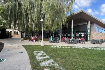 The outside of OhioHealth O'Bleness Hospital is decorated with signs that say OU, Oh Yeah and Go Cats, and the grass and sidewalks have OHIO decorations. In addition, there is a giant football under a tree.