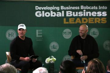 James Clear and Ryan Hawk speak in front of a large crowd in Nelson Commons