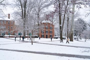 Individuals walk across the snowy College Green at Ohio University