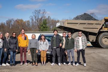 Voinovich Research Scholars and OHIO administrators are shown in front of a large dump truck at a work site