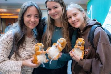 Three OHIO students hold stuffed animal squirrels at an OHIO Giving Day event