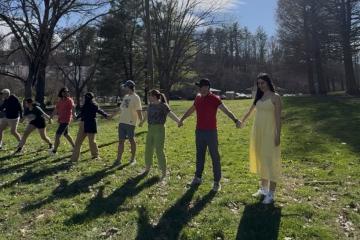 OHIO students hold hands while standing in a line outside as part of a game during the Nowruz celebration.