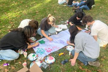 OHIO students paint together on canvases outside in the grass