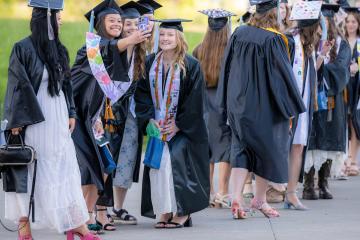 OHIO Lancaster graduates in caps and robes stand together outside for photos and to talk with each other