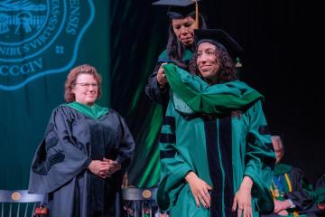 Student is hooded at HCOM commencement