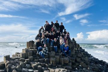 a large group of students poses for a picture by the seaside