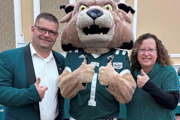 Tracy Watson and Corey Boby stand with the Rufus mascot while inside the Baker University Center Ballroom