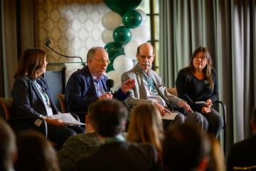 Four panel members lead a discussion on the stage at the State Government Alumni Luncheon