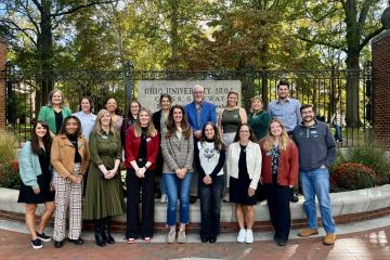 Scripps Young Alumni Council members stand together in front of the College Gate and the College Green