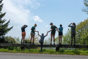 OHIO students stand  together outside on a warm summer day while looking out across a valley