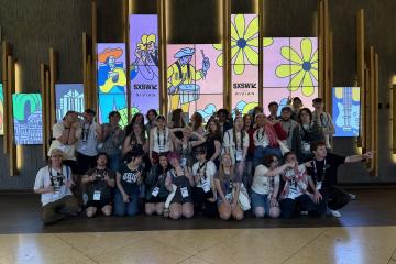 A large group of OHIO students pose for a picture in front of a SXSW sign