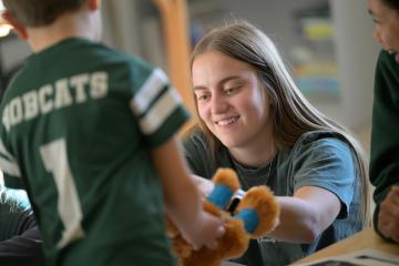 An OHIO teacher or assistant works with a child wearing an Ohio University football shirt at the Child Development Center