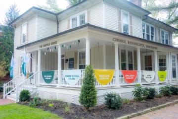 The outside of The Burtch House with signage on the front porch that says "The Burtch House. Curious, Resourceful, Innovative"