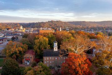 Cutler Hall is shown surrounded by colorful trees, with hilldsides in the background in this aerial image