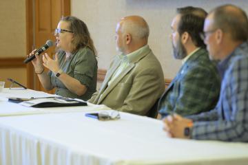 Panelists sit at a table and speak during a Public Service Day event