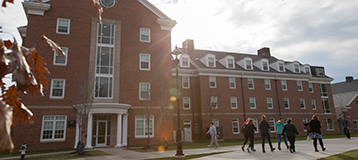 people walking on sidewalk in front of a residence hall