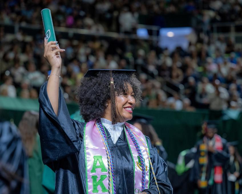 a student holding their diploma placeholder at commencement