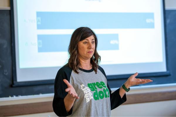 green dot trainer speaks to the audience in front of a projector screen