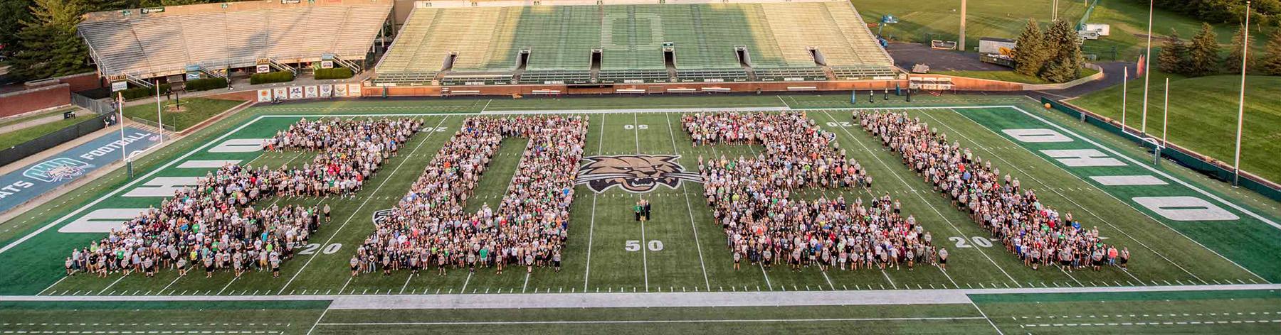 Members of the Class of 2021 stand on the OHIO football field, spelling out 2021 together