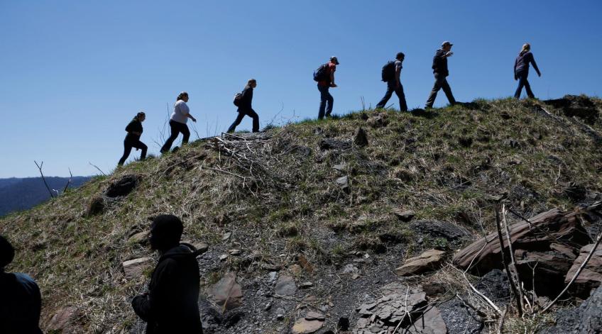 Silhouette of 7 students walking up a mountain