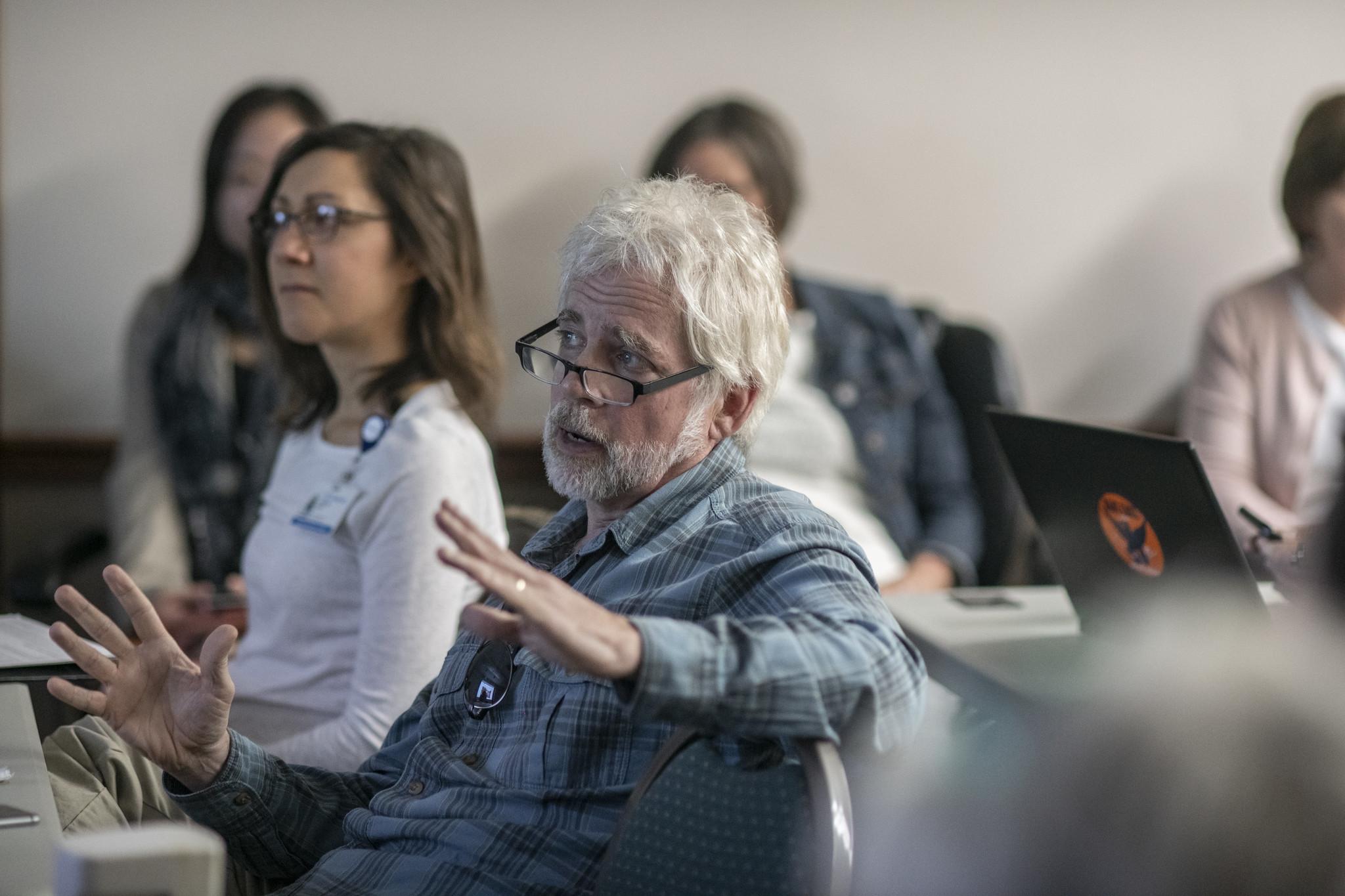 An senior man speaks at a public meeting.
