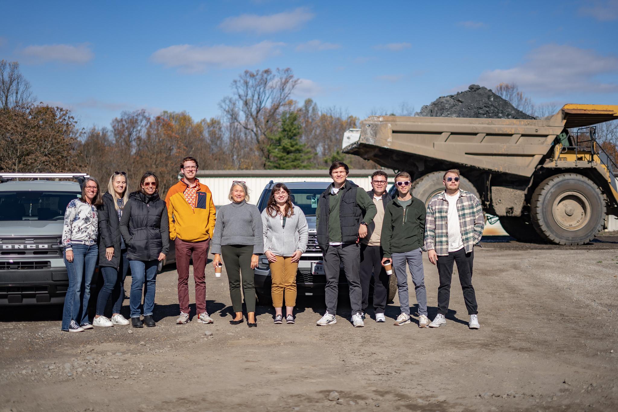 A group of students and professionals gather for a photo at a utility site.